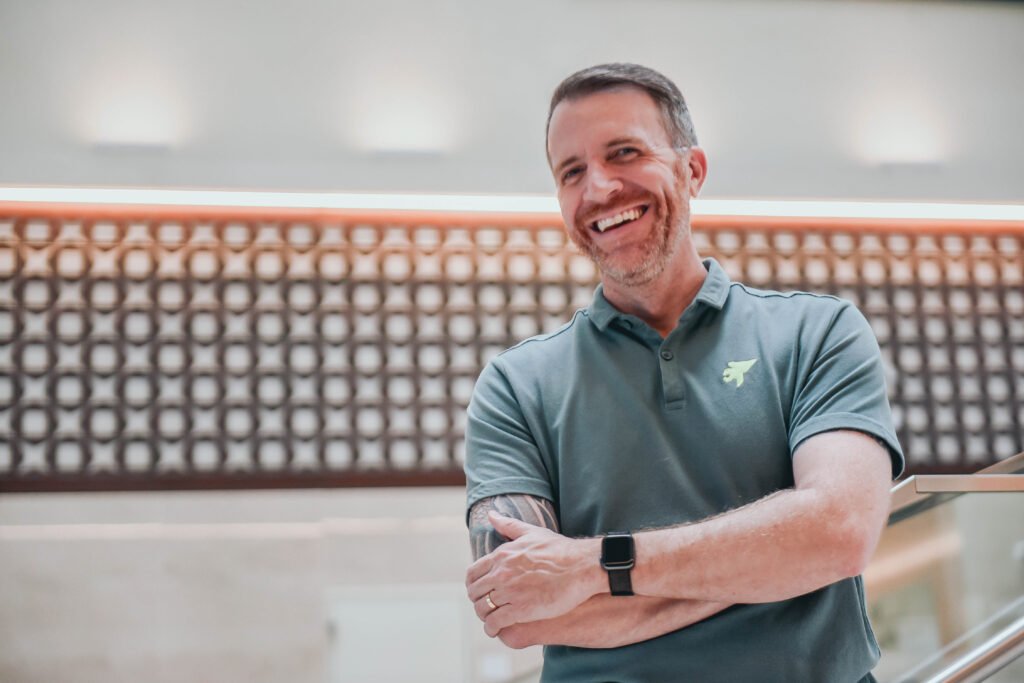 Profissional em ambiente de trabalho com postura aberta e expressão acolhedora